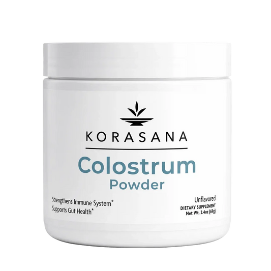A white plastic jar of KORASANA Colostrum Powder with a white lid, featuring a clean white label with black and blue text on a solid white background.