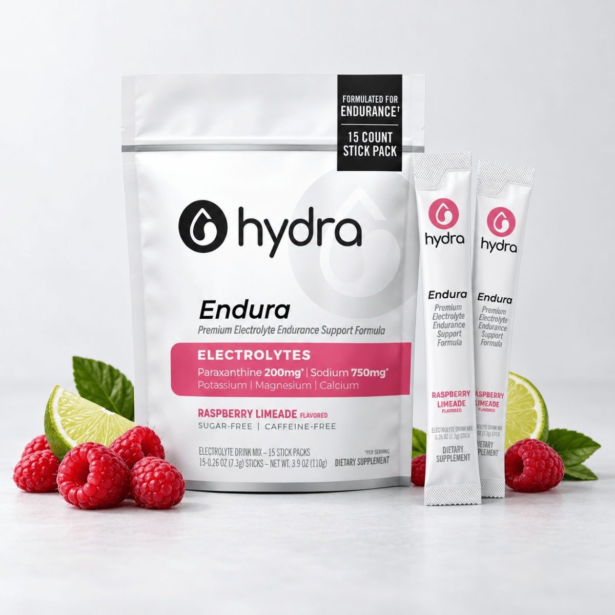 Hydra Endura electrolyte support formula in a white resealable pouch with two single-serve stick packs, styled with raspberries, lime slices, and mint leaves on a light gray background.